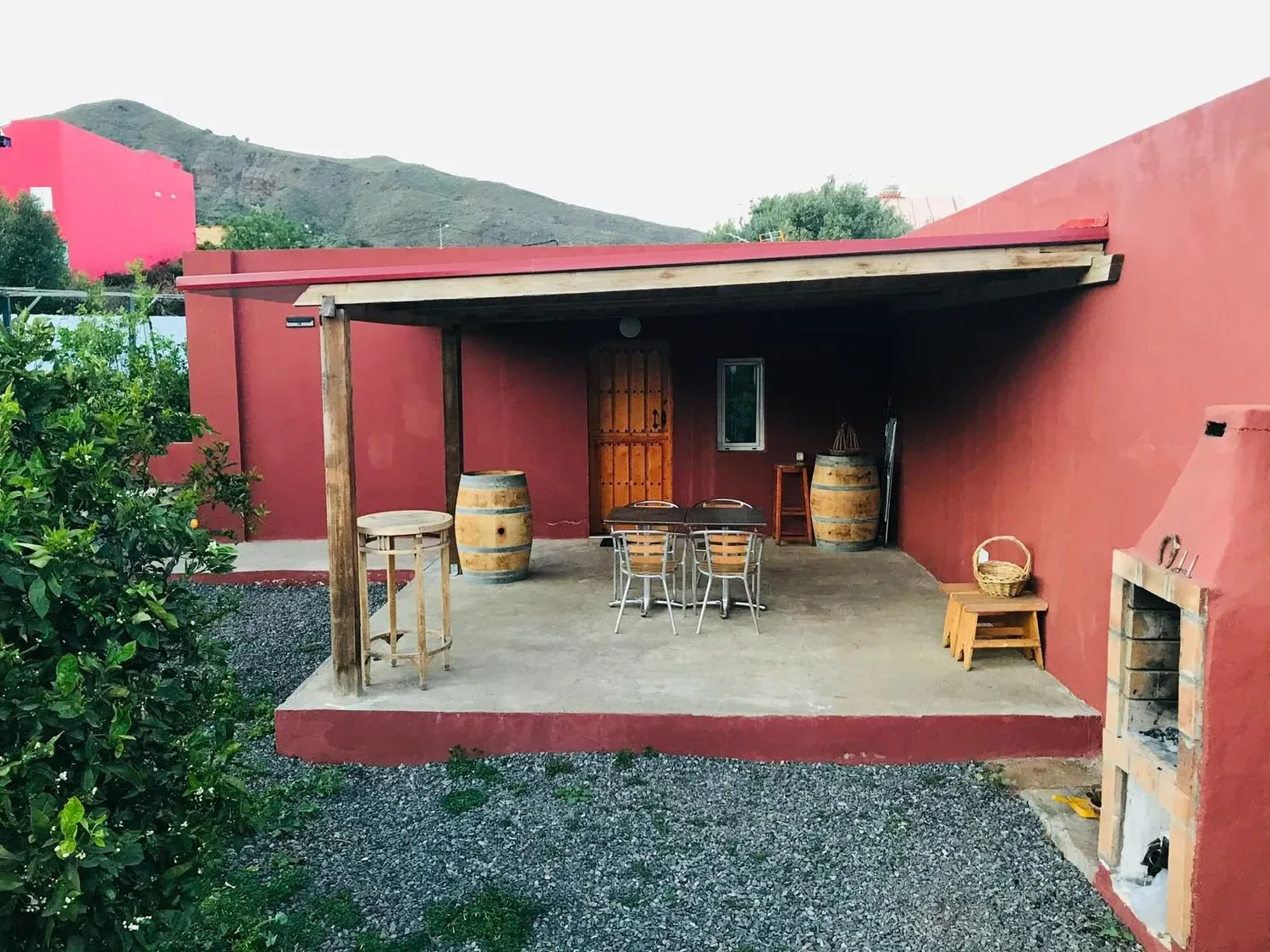 Porche del proyecto Telde 2 terminado, fachada tierra rojiza y mobiliario exterior
