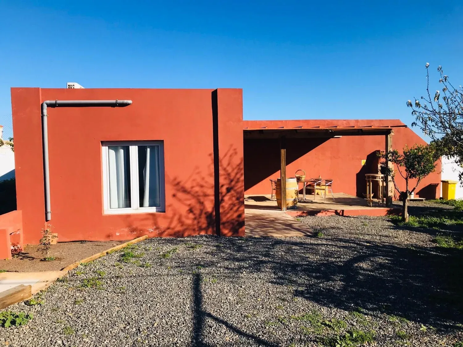 Casa rural reformada en Telde con fachada tierra rojiza y porche